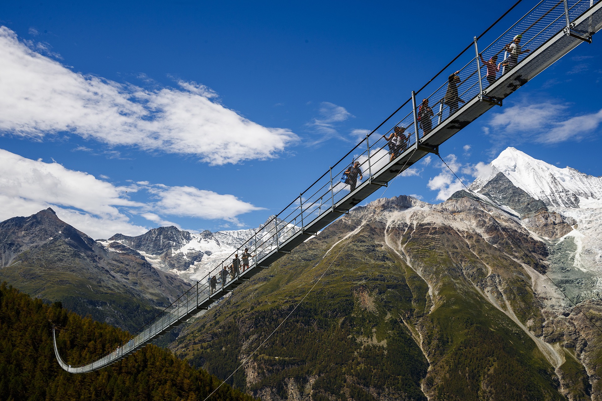 People walk on the "Europabruecke", that is supposed to be the world's longest pedestrian suspension bridge with a length of 494m, after the official inauguration of the construction in Randa, Switzerland, on Saturday, July 29, 2017. The bridge is situated on the Europaweg that connects the villages of Zermatt and Graechen. (Valentin Flauraud/Keystone via AP)